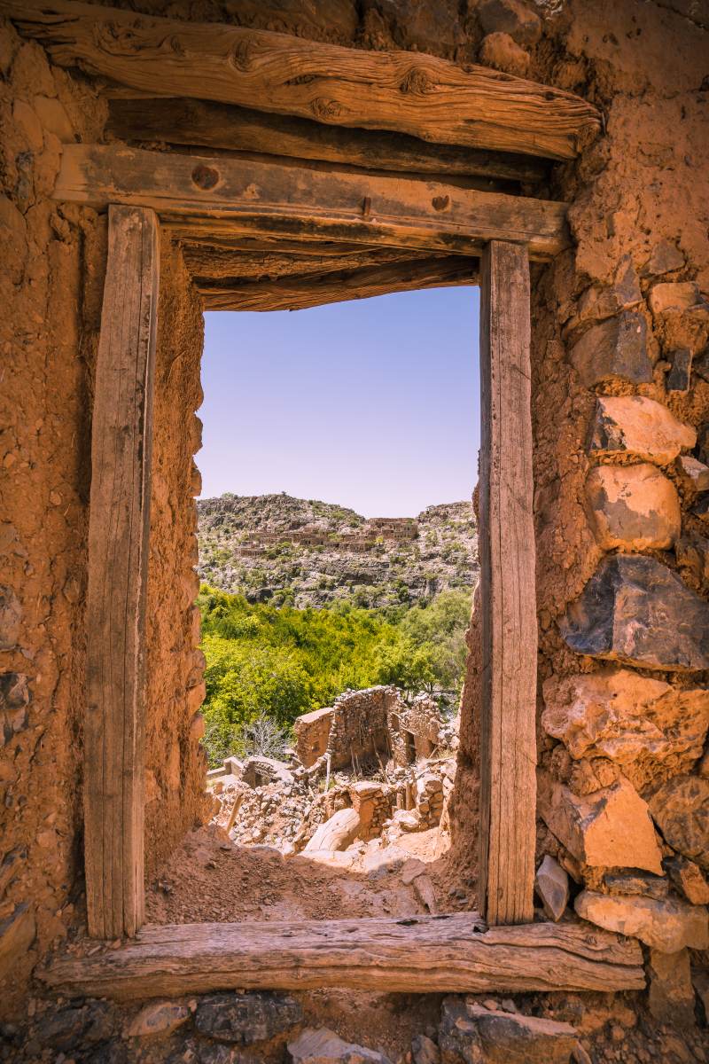 A view trough a window of an abandoned house, lookin out to a mountain escarpment