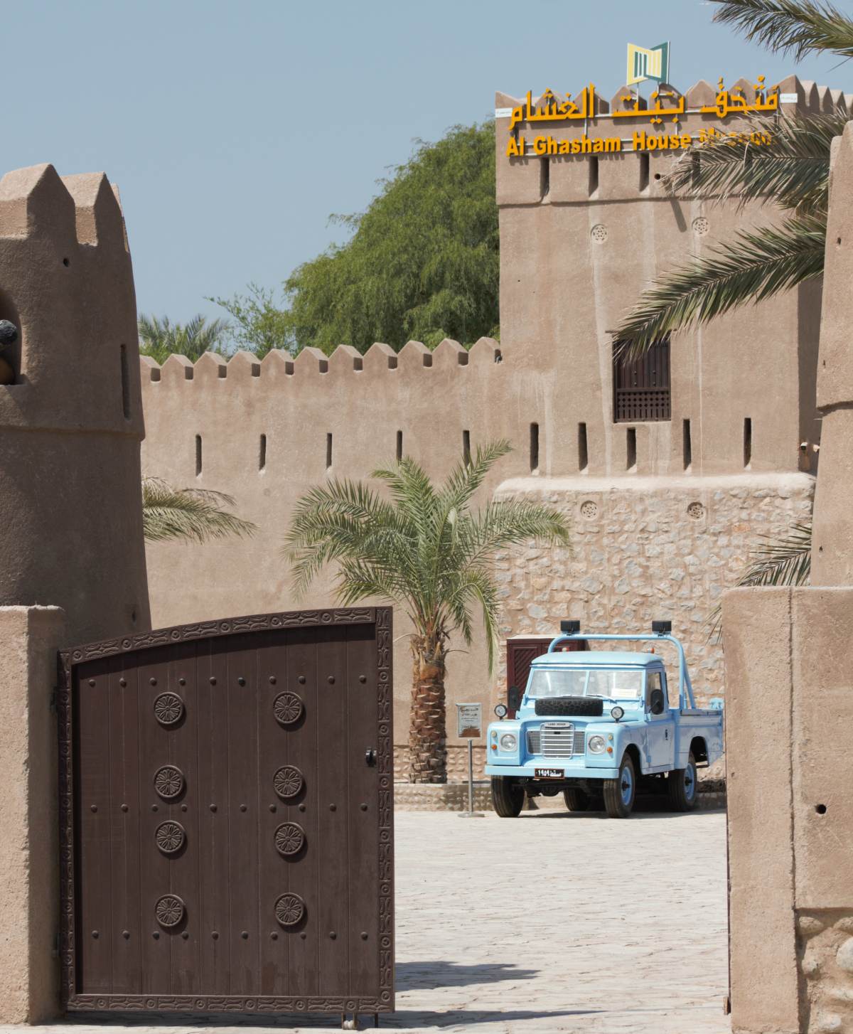A picture taken through the gates of Al Ghasham House with a LandRover parked in the gardens