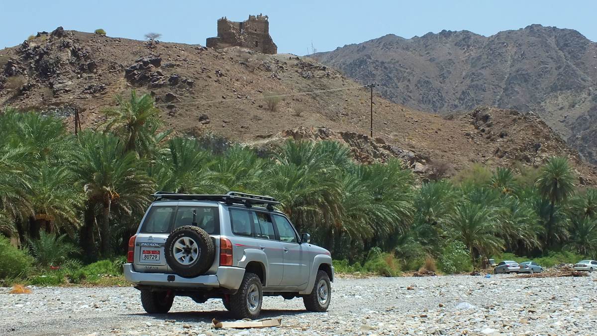 A Nissan Patrol drives past a watchtower perched on the hill