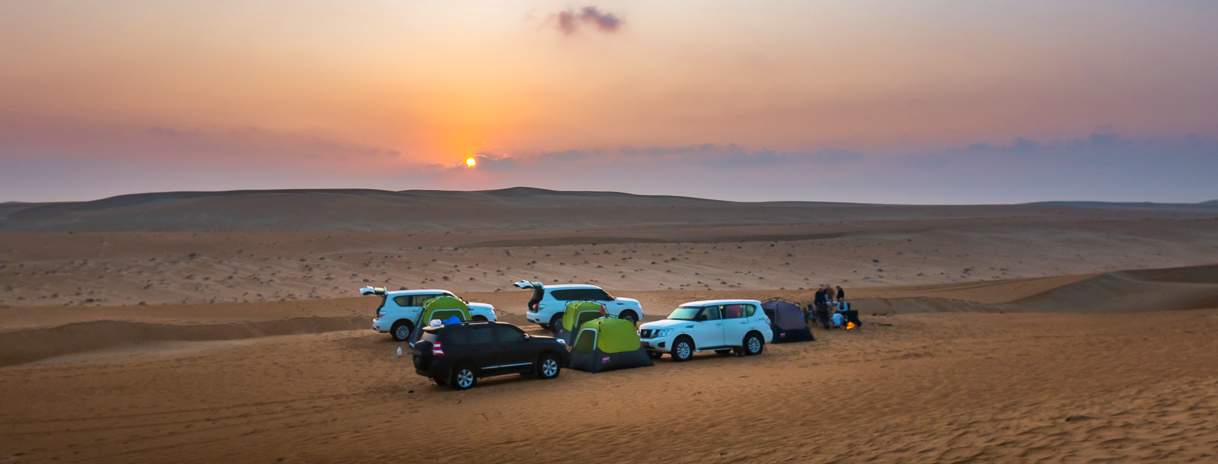 Cars and tents at sunset in the desert