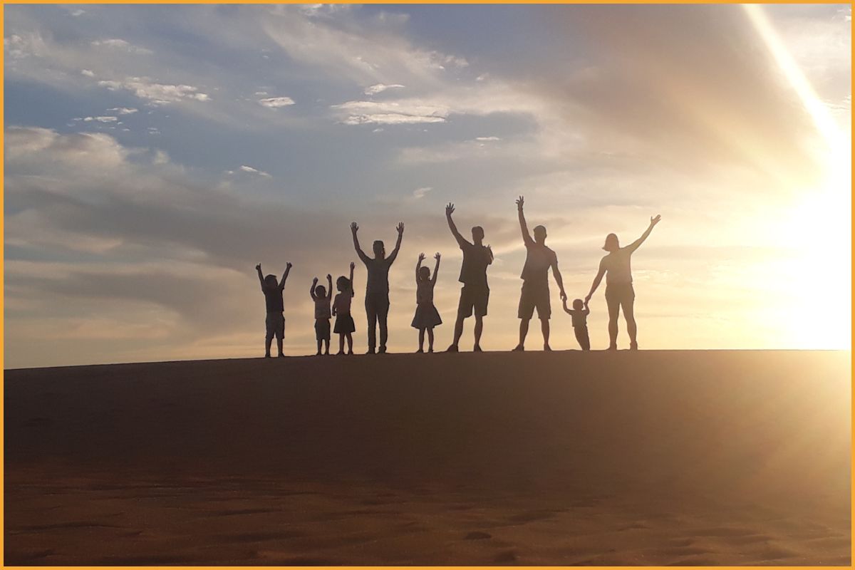 Parents and children silhouetted on a desert dune at sunset in the Arabian Peninsula